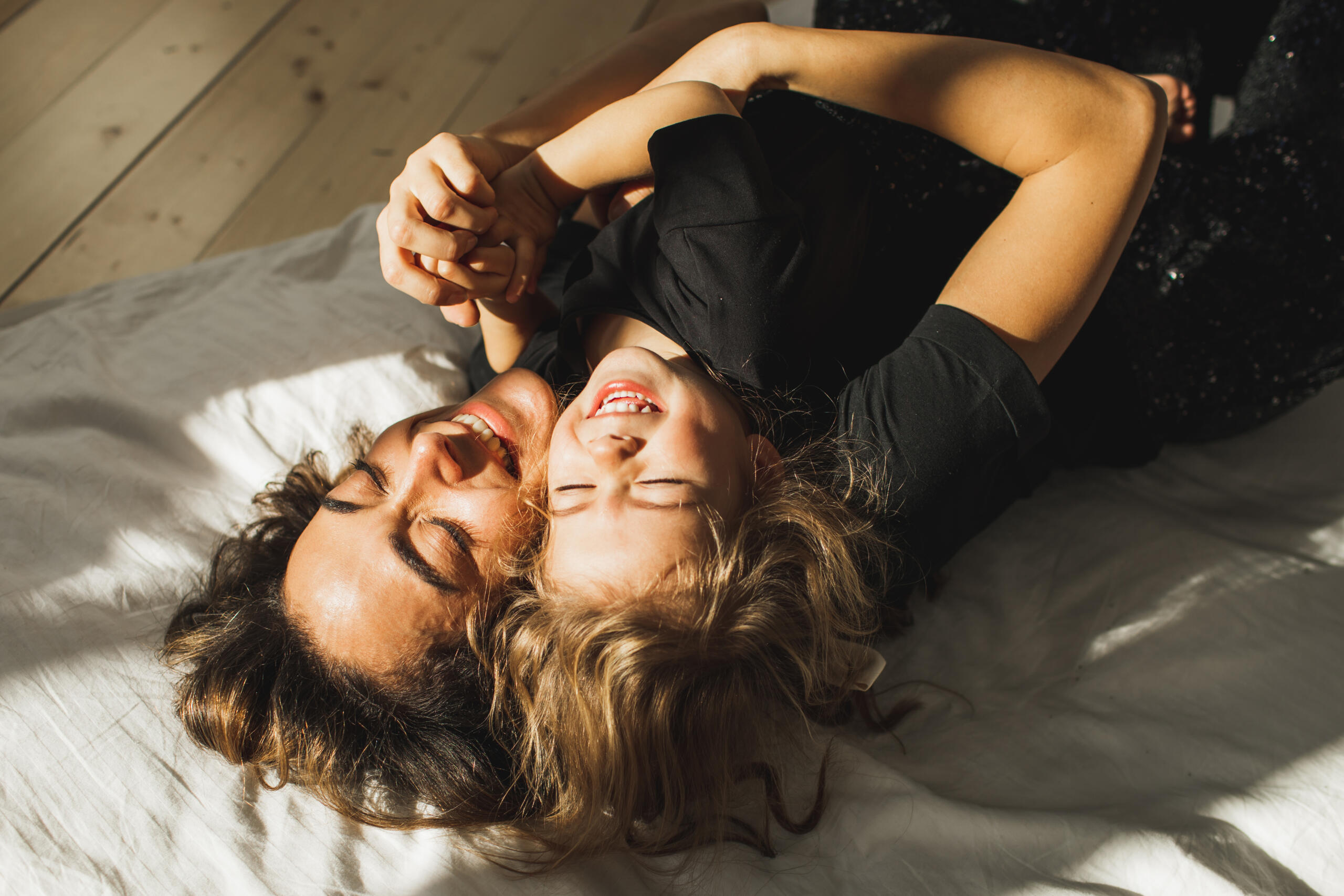 Beautiful mother and daughter having fun in bed.